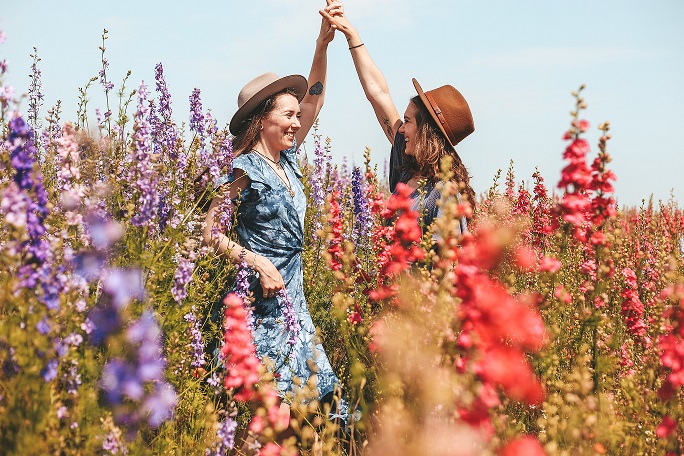 Two grateful women celebrating their success in field of flowers.