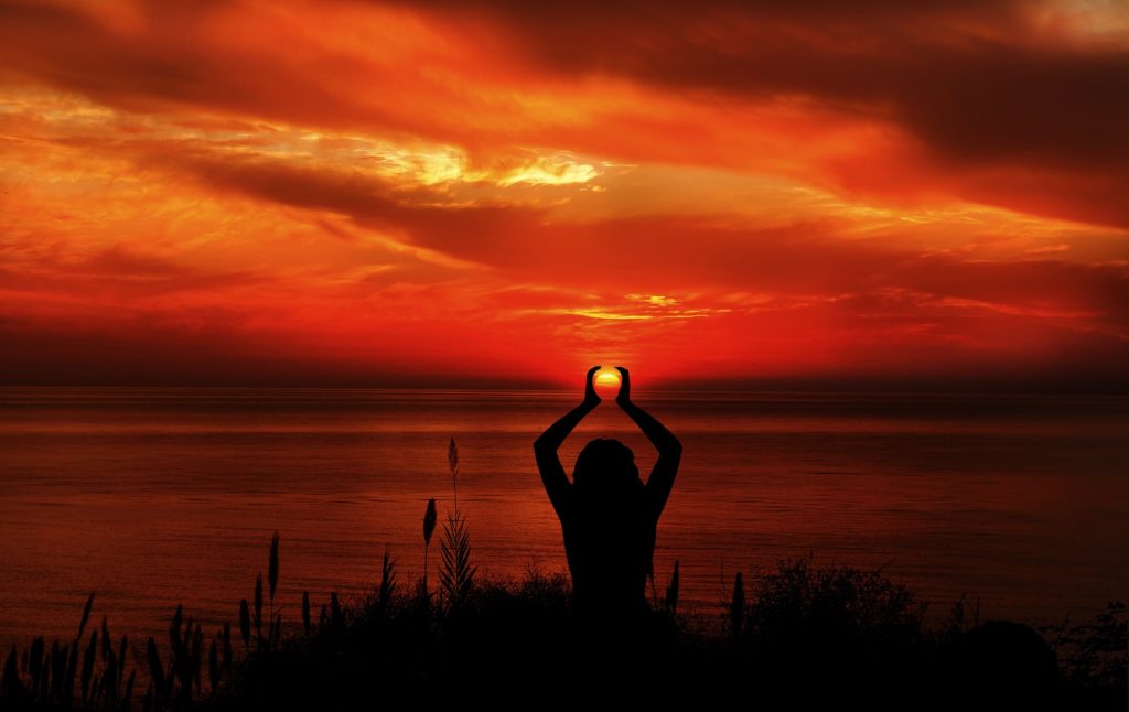 Woman meditating on desires at sunset.